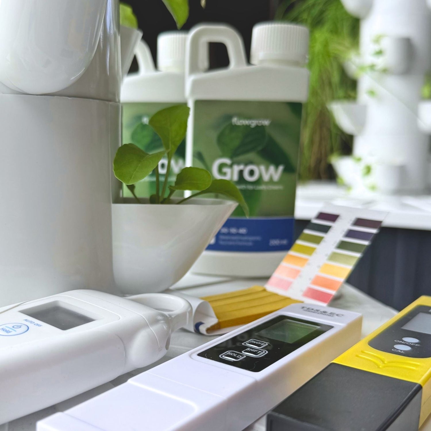 A collection of Digitial EC meters, pH test Meter and pH stips sitting on a vertical hydroponic system in a New Zealand Home