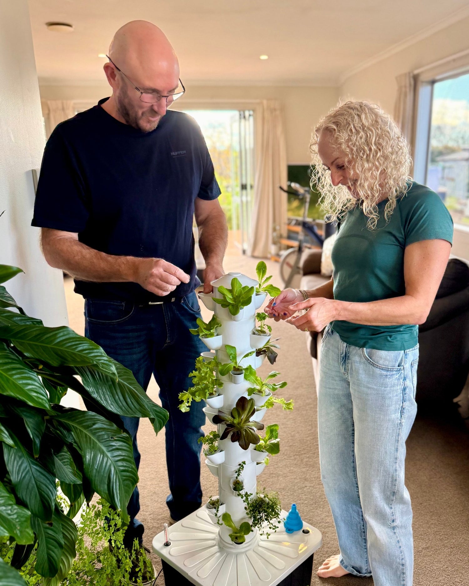 FlowGrow founders checking herbs growing in a hydroponic tower at home